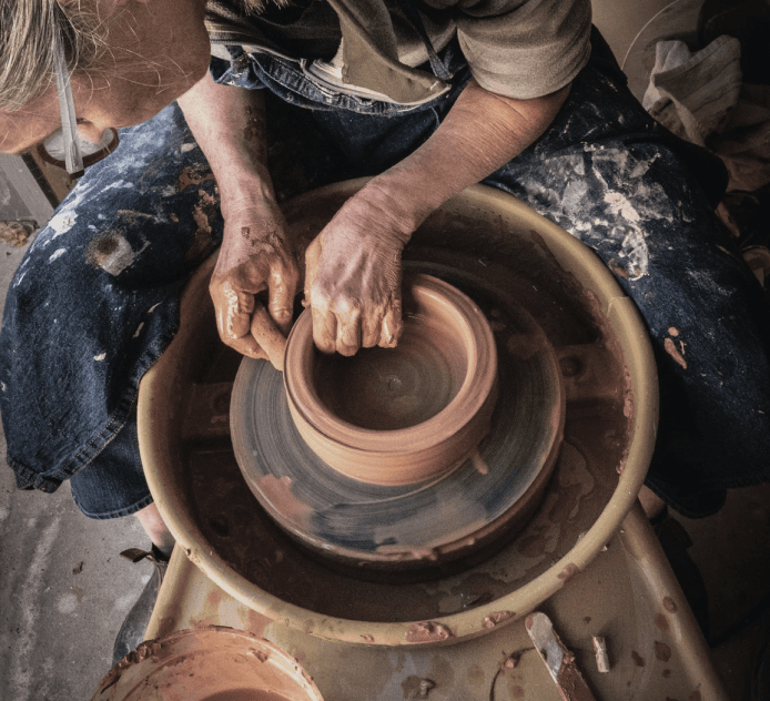 Artisan shaping pottery by hand on a traditional wheel