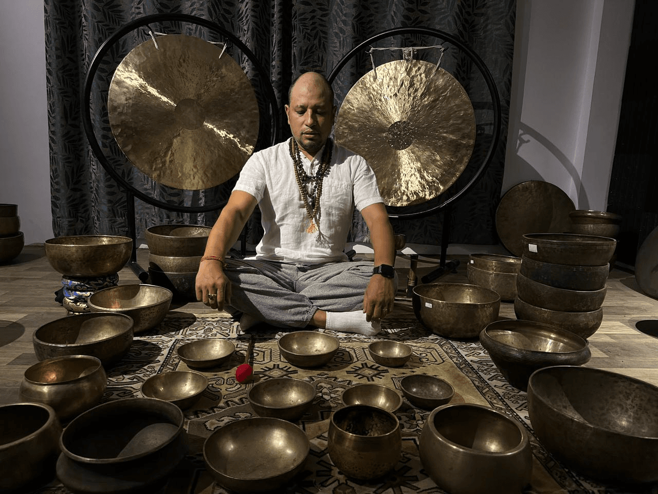 Meditation teacher seated with singing bowls during a healing session